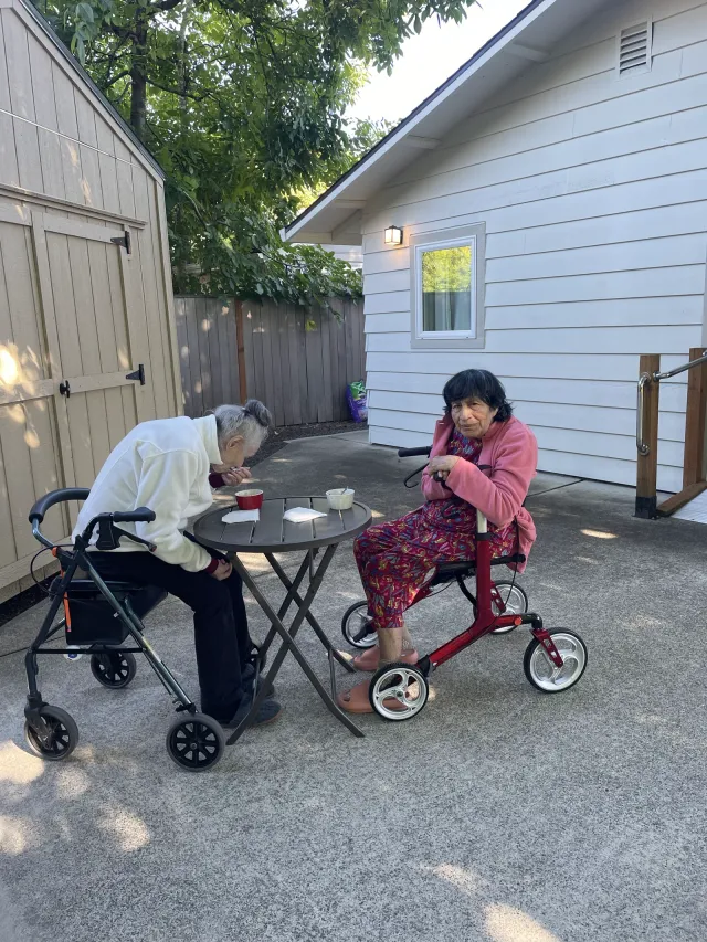 Two residents sitting together at a patio table in the backyard.